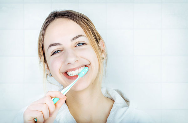 woman brushing her teeth and smiling